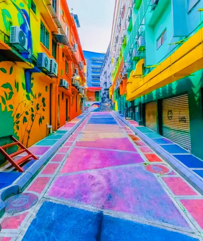 This area, once a typical back alley, has been transformed into a captivating outdoor art gallery by commissioned artists, featuring colorful murals and street art, including a section resembling a stream cascading through a jungle. 